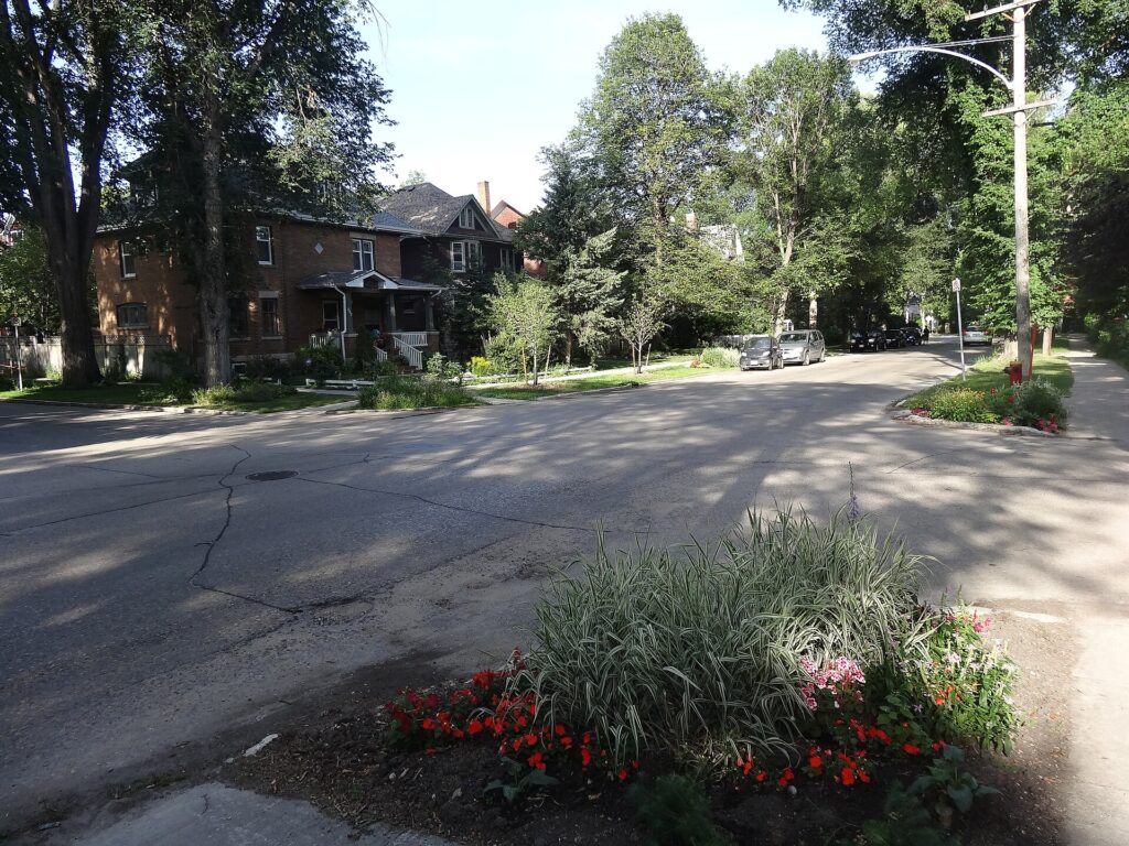 Brick and wood-frame character houses on a tree-lined street in Wolseley, in Winnipeg's West End